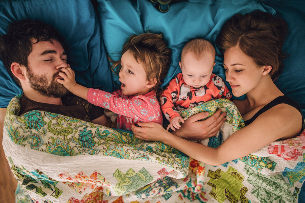 Humana Glückliche Familie liegt kuschelnd im Bett